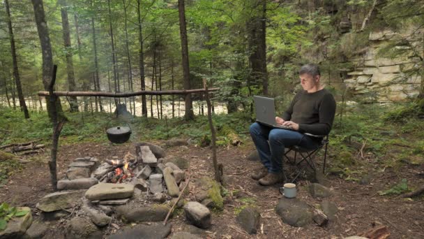 Man Works Laptop Campfire Beautiful Forest Concept Freelancing Digital Nomad — Stock videók