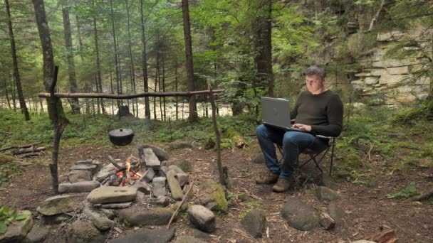 Man Works Laptop Campfire Beautiful Forest Concept Freelancing Digital Nomad — Video Stock