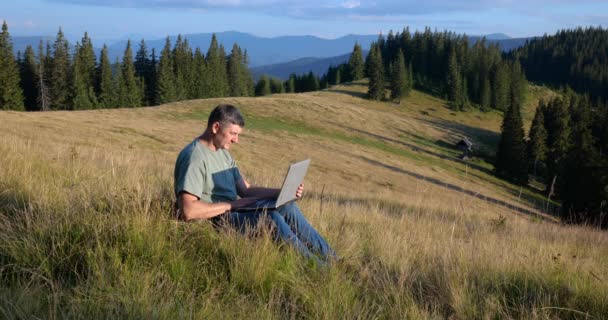 Man Sits Beautiful Meadow Mountains Works Laptop Concept Freelancing Digital — Vídeo de Stock