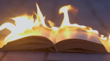An open book is on fire. Big bright flame, burning paper on old publication in the dark. Book Burning - Censorship Concept, 4K