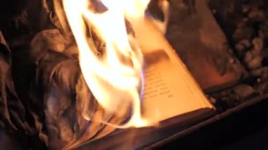 An open book is on fire. Big bright flame, burning paper on old publication in the dark. Book Burning - Censorship Concept, slow motion, close-up, 4K