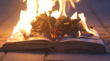 An open book is on fire. Big bright flame, burning paper on old publication in the dark. Book Burning - Censorship Concept, 4K