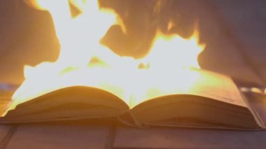 An open book is on fire. Big bright flame, burning paper on old publication in the dark. Book Burning - Censorship Concept, 4K
