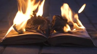 An open book is on fire. Big bright flame, burning paper on old publication in the dark. Book Burning - Censorship Concept, 4K