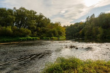 Nehir sonbahar ormanından akıyor. Sonbaharda gün batımından önce nehir