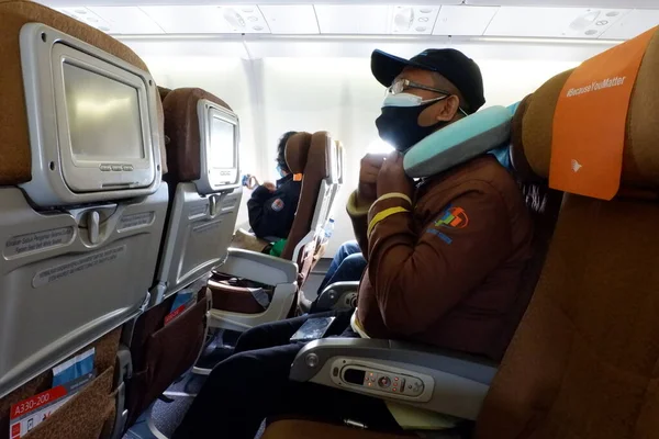 man in protective mask and gloves sitting on the floor in the airport