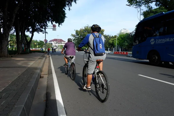 a man in a white t-shirt riding a bicycle in the city