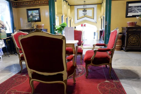Istana Maimun Medan, Indonesia - November 16, 2021: Beautiful living room with Interior Design consist of red chairs, a carpet, yellow wall, painting on the wall
