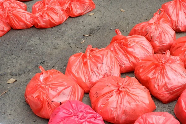Asfaltta düzgünce yerleştirilmiş eti içeren kırmızı plastik torbalar.