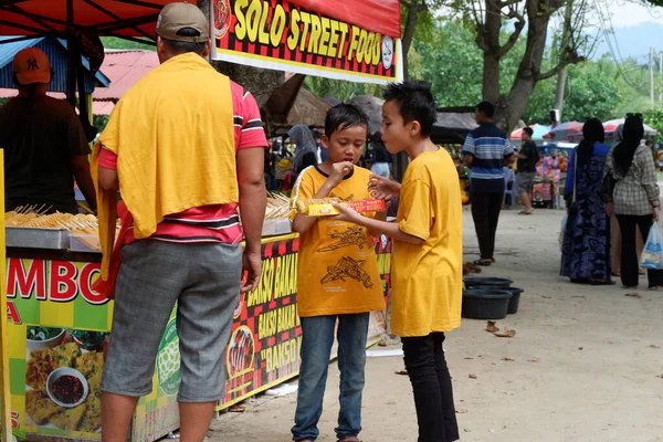 Lampung, Endonezya - 14 Mayıs 2022: Sarı gömlekli iki çocuk markette atıştırmalıkların tadını çıkarıyor
