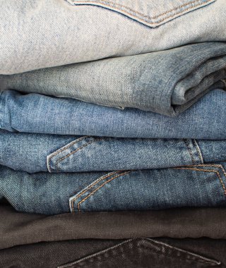 Farklı renklerde kotlar yığılmış. Dükkandaki Denim. Kot yığını. Doku ve arka plan için Denim. Satış konsepti. Kara Cuma indirimi.