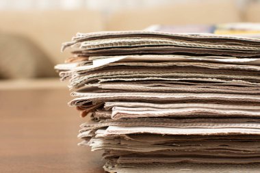 Kağıt yığınları, arka planda bulanık arkaplanı olan ahşap masanın üzerinde yatıyor ve metin için alanı kopyalıyor. Gazete destelerini kapatın. Gazeteci konsepti.