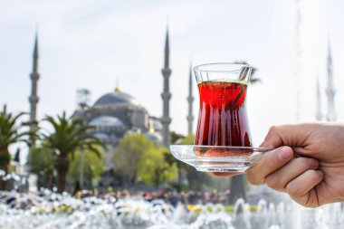 Türkiye 'nin İstanbul kentindeki Sultanahmet Camii' nin (diğer adıyla Sultanahmet Camii) önünde geleneksel Türk çayıyla el ele tutuşan kadın. İstanbul 'un başlıca eğlenceleri.