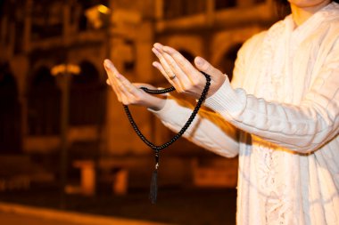 Tespih taşıyan Müslüman bir kadının eli. Cami önünde namaz kılmak. Ramazan Kareem. Ramazan Mübarek kavramı.
