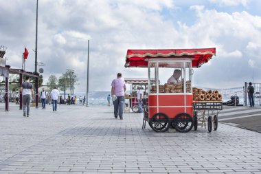 ISTANBUL, TURKEY - 10 Eylül 2019: Karaköy Embankasında (Karaköy İskelesi) geleneksel Türk sokak yemekleri satan adam. İnsanlar deniz kenarında dinleniyor..