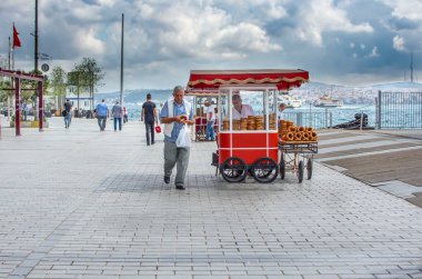 ISTANBUL, TURKEY - 10 Eylül 2019: Karaköy Embankasında (Karaköy İskelesi) geleneksel Türk sokak yemekleri satan adam. İnsanlar deniz kenarında dinleniyor..