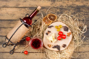 Bir şişe kırmızı şarap ve peynirli domates, zeytin ve fındık. Şarapla romantik bir akşam yemeği. Üst görünüm.