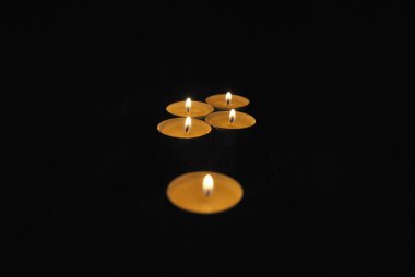 Burning candles in a dark room. Tealight. The flames light up the darkness.