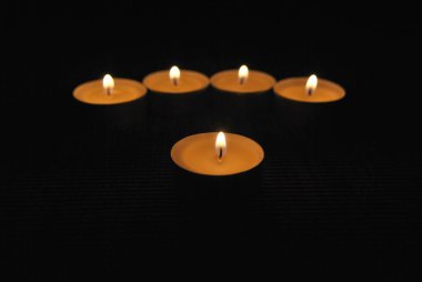 Burning candles in a dark room. Tealight. The flames light up the darkness.
