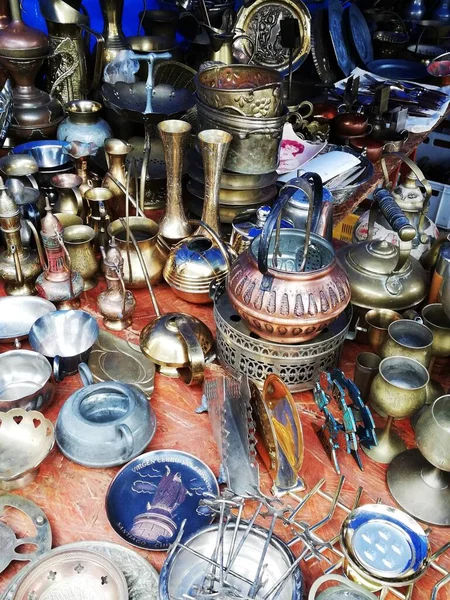 Flea market in the town square. Lots of junk and antique utensils. 