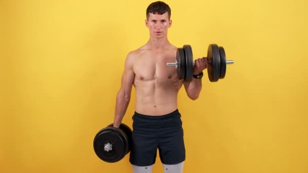 М'язистий сильний хлопець піднімає фітнес-штангу на жовтому фоні, потужність — стокове відео