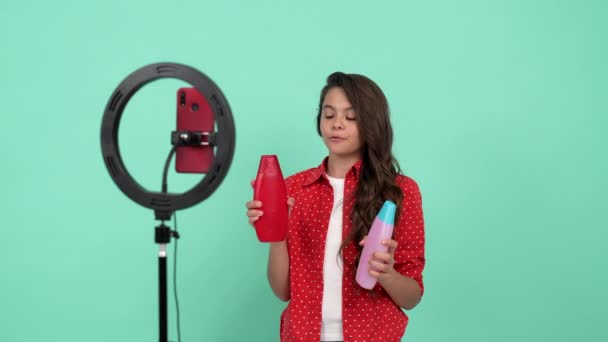 Mutlu genç kız güzellik blogcusu uzun kıvırcık saçlara sahip şampuanın video incelemesini yapıyor.. — Stok video