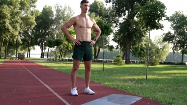 Homem atlético com corpo muscular pronto para o treinamento ao ar livre no parque, motivação — Vídeo de Stock