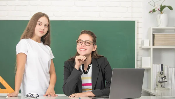 Menina adolescente feliz e tutor na sala de aula da escola com computador, dia dos professores — Fotografia de Stock