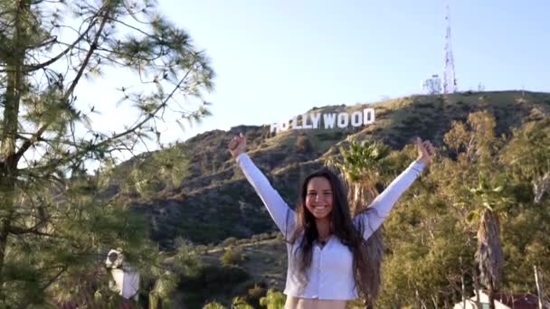 Štěstí a svoboda dívky ukazující palec nahoru a skákání na hollywoodské znamení, radost. — Stock video