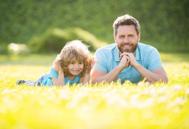 Baba oğul mutlu bir aile. Yaz parkında rahatlayın. Yeşil çimenler, babalık.