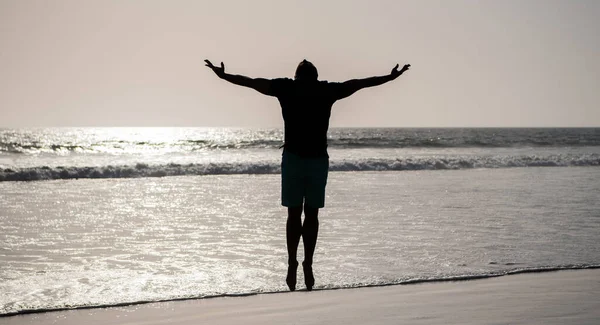 Zdrowy mężczyzna sylwetka podniosłem ręka na plaża. Energiczne lato. poczuj wolność. — Zdjęcie stockowe