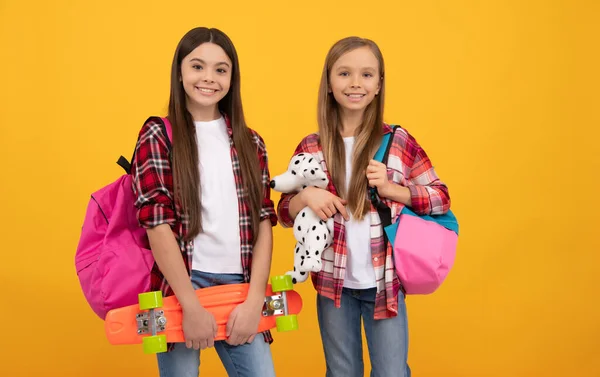 Niños felices en camisa a cuadros casuales llevan el juguete de la mochila y el tablero del centavo, hipster —  Fotos de Stock