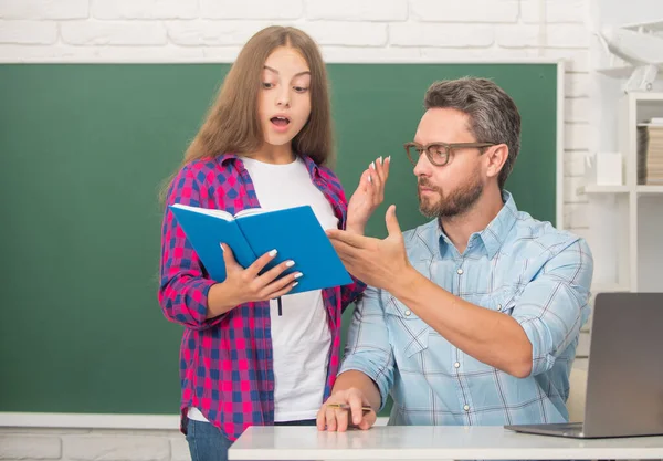 Verbaasd tiener meisje en leraar man op de middelbare school met werkboek op schoolbord, onderwijs — Stockfoto