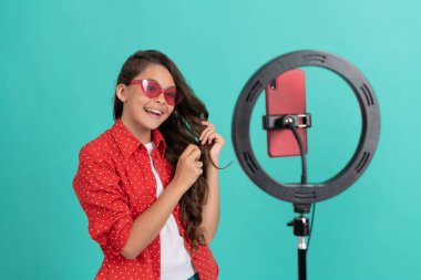 Güneş gözlüklü mutlu çocuk selfie liderliğindeki blogcuyla uzun saçlarını internette gösteriyor.