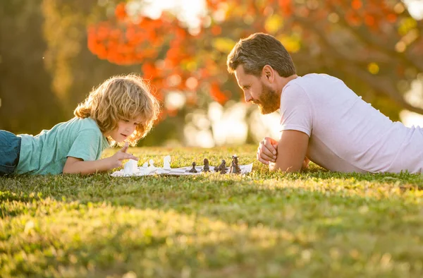 Heureux famille de papa et fils enfant jouer aux échecs sur herbe verte dans le parc en plein air, jouer aux échecs — Photo