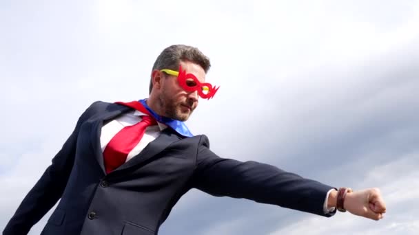 Бізнесмен у супергеройському костюмі з піднятою рукою на фоні неба, успіх бізнесу — стокове відео