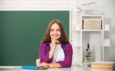 Mutlu çocuk karatahta ve okulda sınıfta oturuyor.