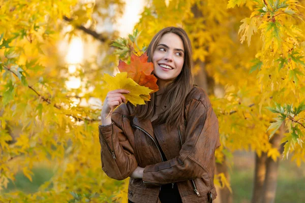 Happy girl with school bag near autumn colorful leaves on rowanberry tree, nature — Stock Photo, Image