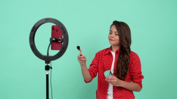 Gülümseyen çocuk etkileyicisi toz fırçasının güzellik ürününü tanıtıyor. Selfie kullanıyor, blog yazıyor. — Stok video