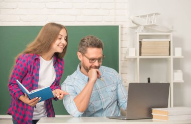 baba ve çocuk eğitimi karatahta arka planında kitap ve dizüstü bilgisayarla, iletişim.