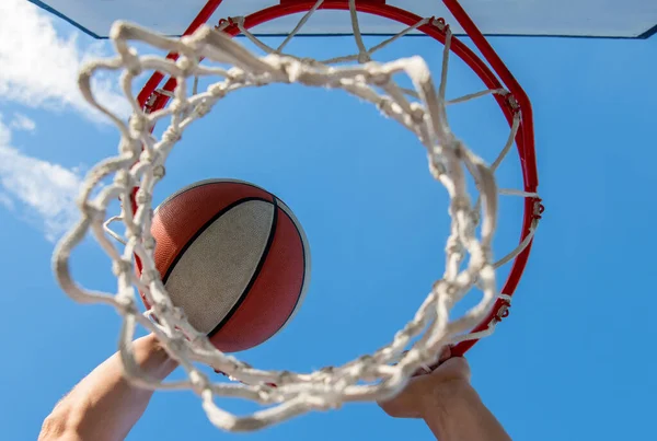 Basketbol oynarken sayı yapmak. Top sepetin içinden geçiyor. Adam topu potaya atıyor.. — Stok fotoğraf