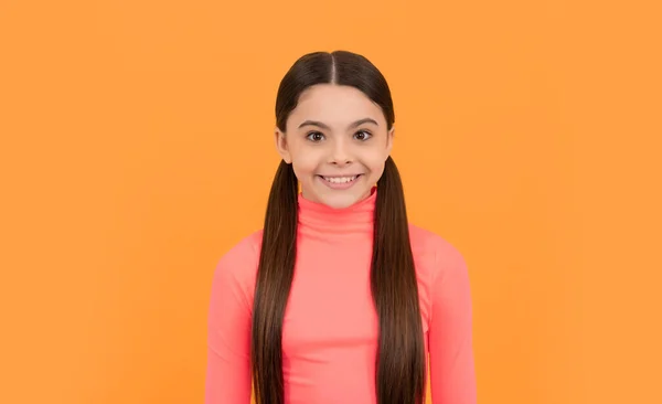 Gelukkig tiener meisje met lang haar op oranje achtergrond, schoonheid — Stockfoto