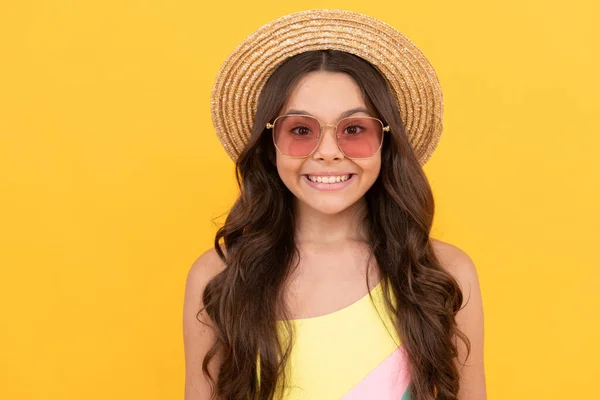 Gelukkig kind in de zomer stro hoed en bril heeft krullend haar op gele achtergrond, zomer stemming — Stockfoto