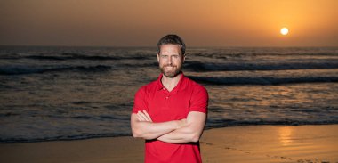 Güneşin doğuşunda, yaz kumsalında, tatilde neşeli bir adam.