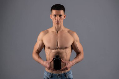 Spor beslenme ürünü. Tişörtsüz adam besleyici besin maddeleri bulundurur. Beslenme takviyeleri