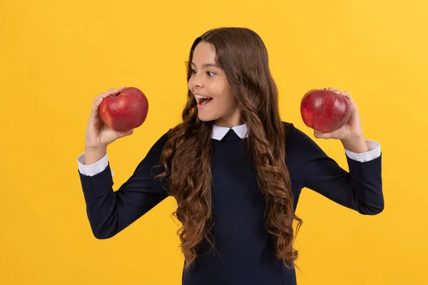 Счастливый подросток выбирает красный витамин яблоко на обед на желтом фоне, выбор — стоковое фото