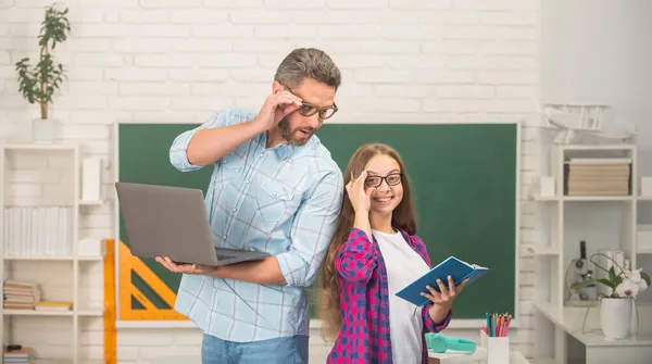 Feliz padre e hijo estudio en la escuela con libro y portátil en el fondo de pizarra, escuela —  Fotos de Stock