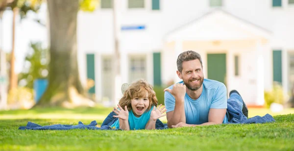 Padre feliz con el niño relajarse juntos en la hierba verde parque, espacio para copiar, día de la familia —  Fotos de Stock