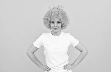 Kıvırcık palyaço peruğu ve kraliçe tacı takmış, parti için neşeli, bencil kadın.