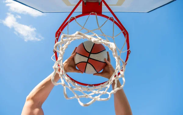 Ο μπασκετμπολίστας ρίχνει την μπάλα στο στεφάνι με φόντο τον ουρανό, στοχεύοντας — Φωτογραφία Αρχείου